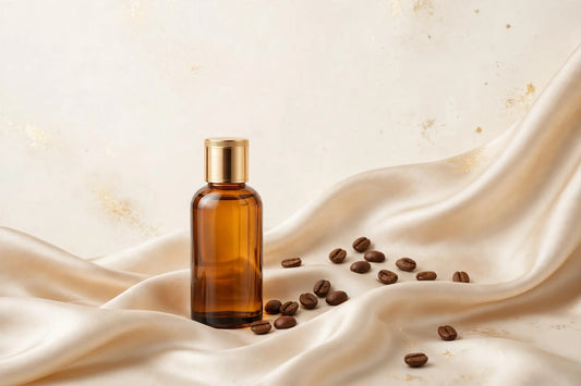 Amber glass caffeine hair growth oil bottle with gold cap beside coffee beans on champagne silk